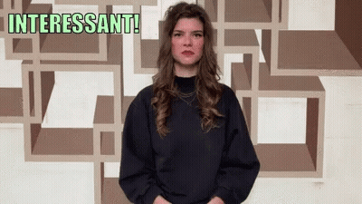 Woman In Front Of Wall Saying Interesting GIF