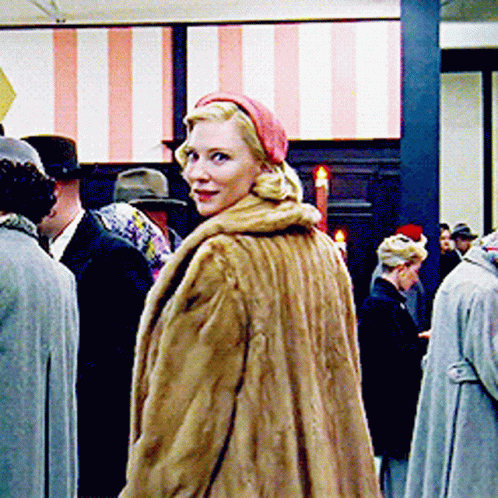 Woman In Fur Coat And Red Hat Standing In Crowd GIF