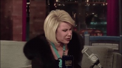 Woman In Fur Coat Sitting At Microphone With Late Show Cup GIF