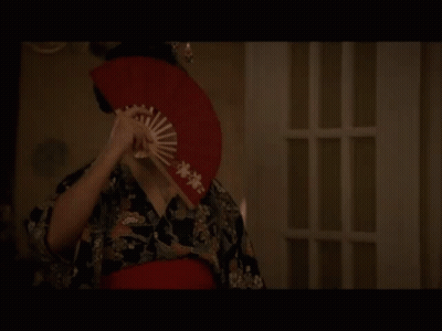 Woman in Geisha Costume Holding Red Fan