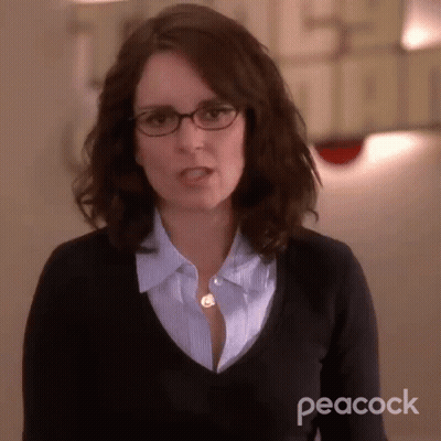 Woman In Glasses And Black Sweater With Peacock Logo GIF