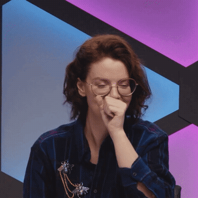 Woman in Glasses and Blue Shirt Covering Mouth