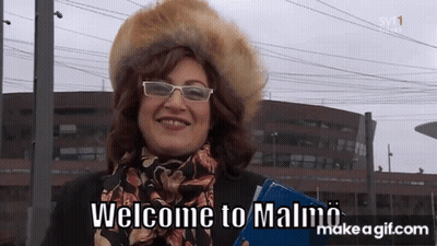Woman In Glasses And Fur Hat Says Welcome To Malmo GIF