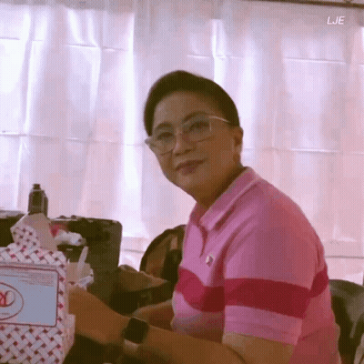 Woman In Glasses And Pink Shirt Sitting By Bag Saying Lje GIF