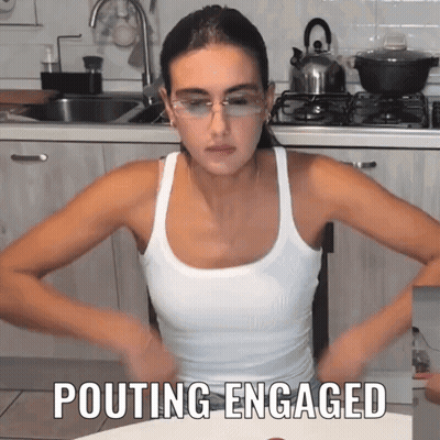Woman In Glasses And Tank Top Pouting In Kitchen GIF