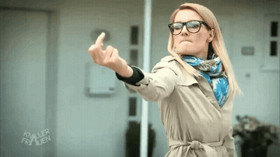 Woman In Glasses And Trench Coat Showing Middle Finger GIF