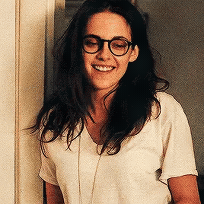 Woman In Glasses And White Shirt Smiling By Door GIF
