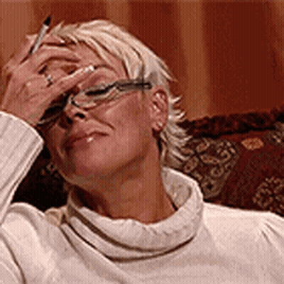 Woman In Glasses And White Sweater Holding Pen To Face GIF