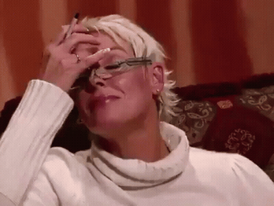 Woman In Glasses Covering Face On Couch GIF