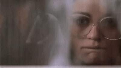 Woman In Glasses Looking Through Window GIF