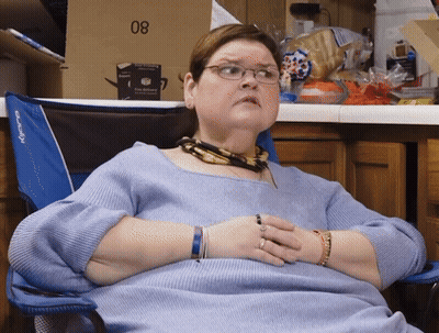 Woman In Glasses Sits In Blue Chair With Box 08 GIF