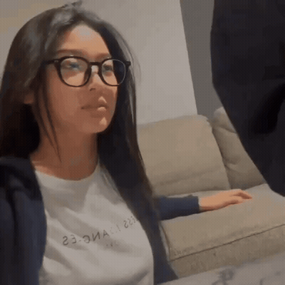 Woman In Glasses Sitting On Couch Looking At Camera GIF