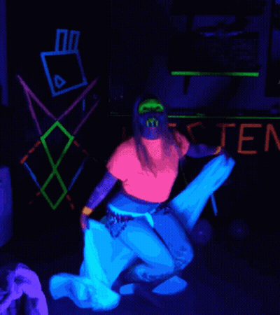 Woman In Glow In The Dark Outfit In Front Of Listen Sign GIF