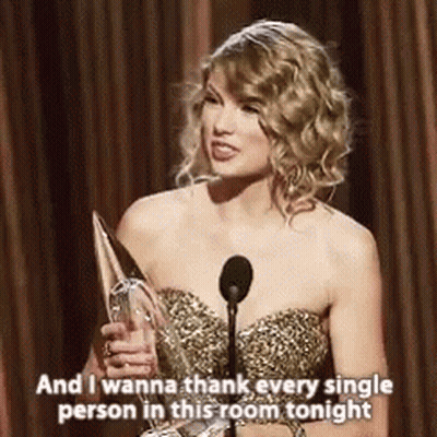 Woman In Gold Dress Holding Trophy And Microphone GIF