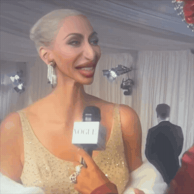 Woman In Gold Dress Interviewed With Vogue Microphone GIF