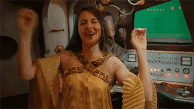 Woman In Gold Dress Raising Arms GIF