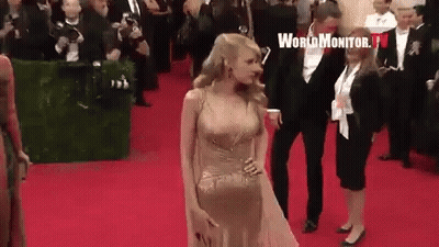 Woman In Gold Dress Walking Red Carpet With Man In Tuxedo GIF