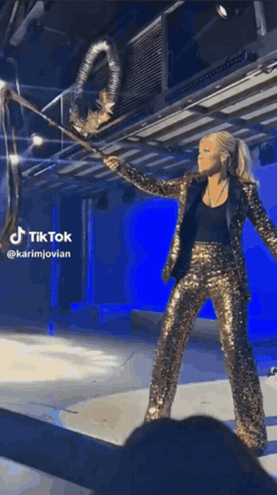 Woman In Gold Sequined Suit Holding Large Object GIF