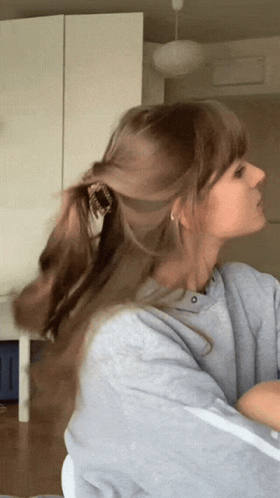 Woman In Gray Sweatshirt Holding Ponytail GIF