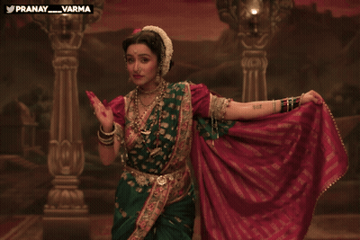 Woman In Green And Red Dress Dancing In Front Of Pranay Varma Painting GIF