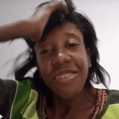 Woman In Green And Yellow Smiling Holding Head GIF