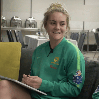 Woman In Green Australia Jacket On Couch GIF