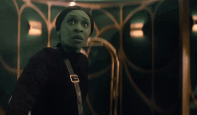 Woman In Green Costume Next To Woman In White Dress GIF