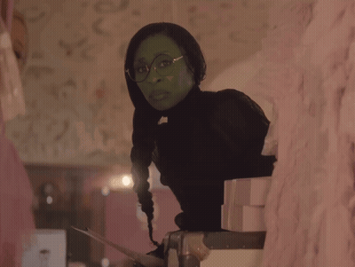 Woman In Green Dress And Green Hat Sitting On Couch GIF