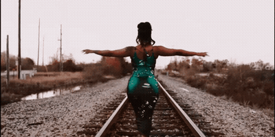 Woman In Green Dress On Train Tracks GIF