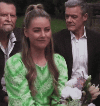Woman In Green Dress Smiling With Bouquet GIF