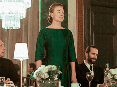 Woman In Green Dress Standing Before Group At Table GIF