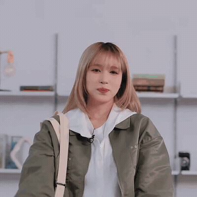 Woman In Green Jacket And White Shirt Waves GIF