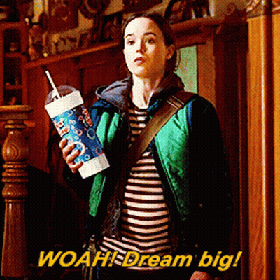 Woman In Green Jacket Holding Cup Saying Woah Dream Big GIF