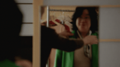 Woman In Green Jacket Smiling At Mirror GIF