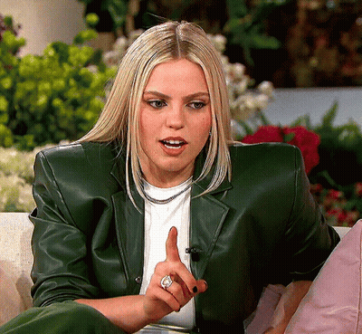 Woman In Green Leather Jacket Sitting On Couch Pointing GIF