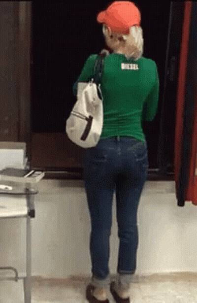 Woman In Green Shirt And Blue Jeans Holding White Bag GIF