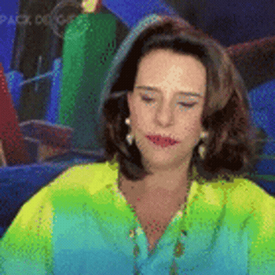 Woman In Green Shirt And Earrings Sitting In Front Of Mirror GIF