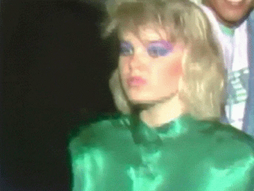 Woman In Green Shirt And Purple Makeup Next To Man GIF