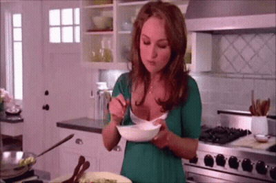 Woman In Green Shirt Eating Bowl Of Food In Kitchen GIF