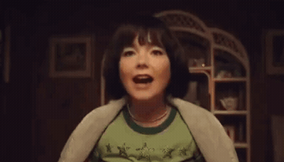 Woman In Green Shirt Screaming In Dark Room GIF