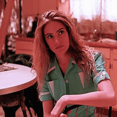 Woman In Green Shirt Sitting At Round Table GIF