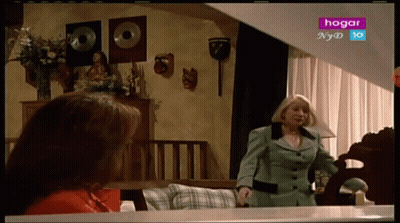 Woman In Green Suit In Front Of TV Saying Hogar GIF