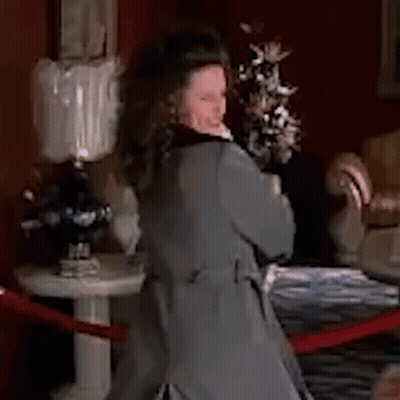 Woman In Grey Coat Standing By Flowers GIF