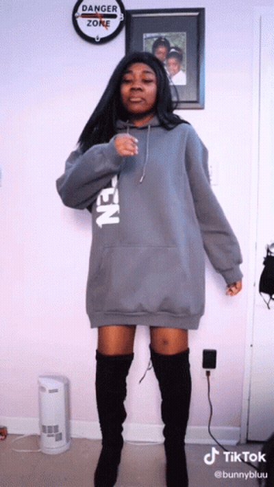 Woman In Grey Hoodie And Black Boots In Front Of Danger Zone Sign GIF