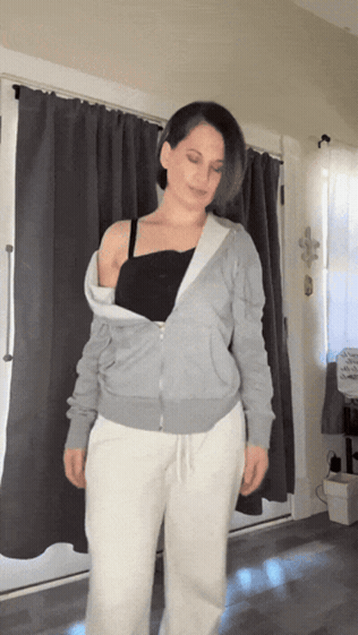 Woman In Grey Hoodie And White Sweatpants By Window GIF