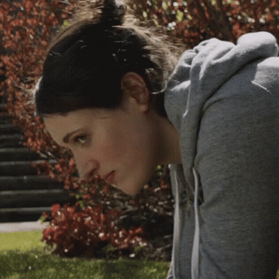 Woman In Grey Hoodie Looking Down At Camera GIF
