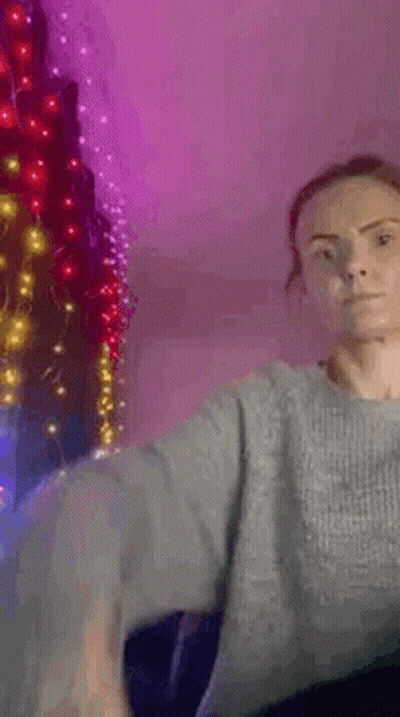 Woman In Grey Sweater By Christmas Tree With Lights GIF