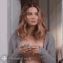 Woman In Grey Sweater Holding Cell Phone GIF