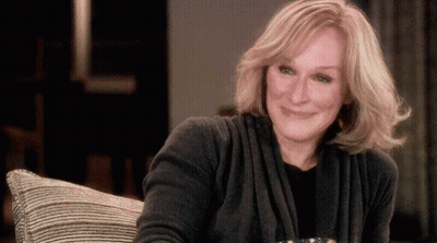 Woman In Grey Sweater Smiling On Couch GIF