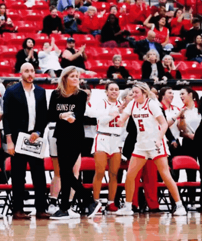 Woman In Guns Up Shirt Walking On Basketball Court GIF
